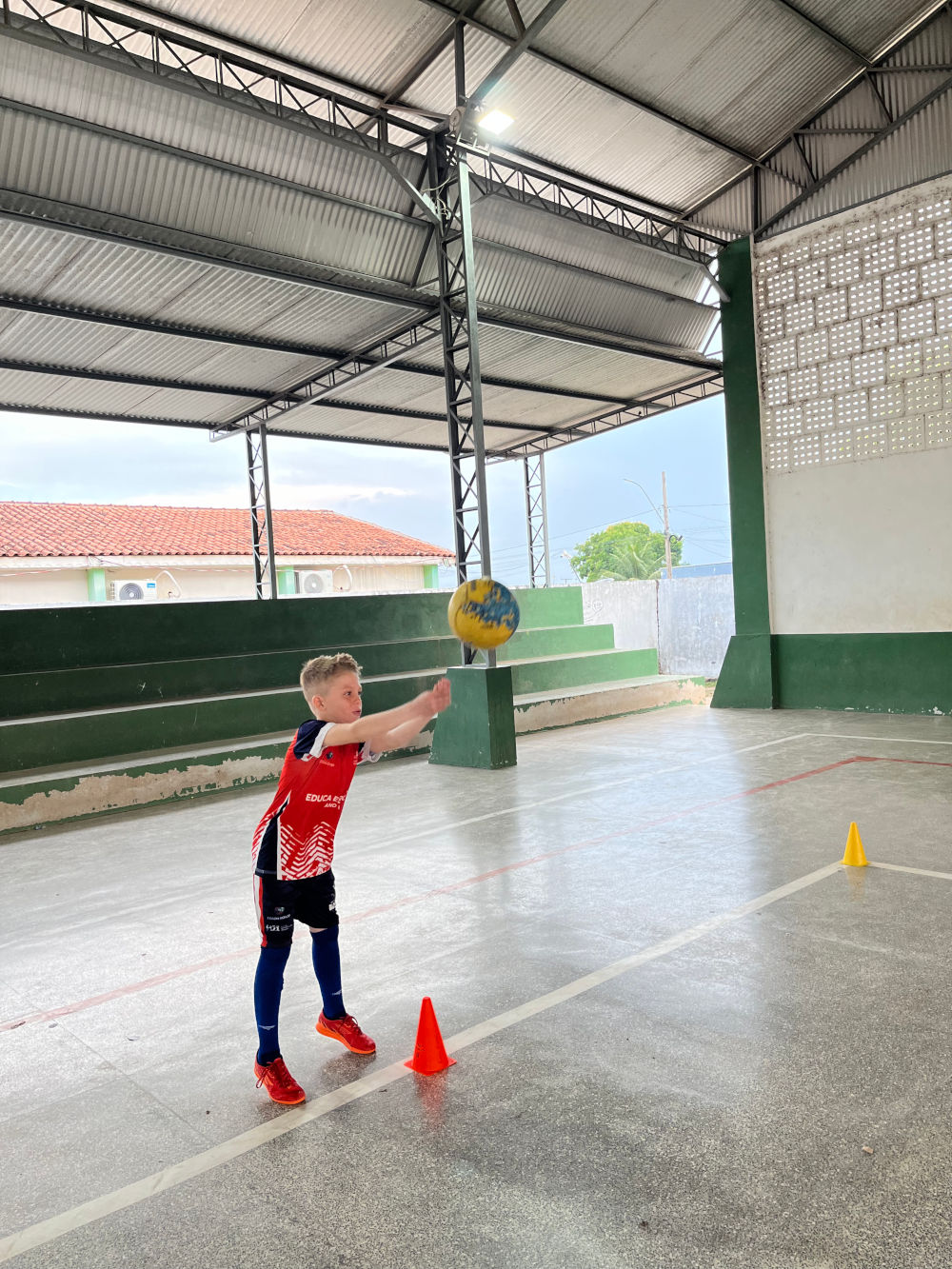 Criança participa de atividade de vôlei na quadra